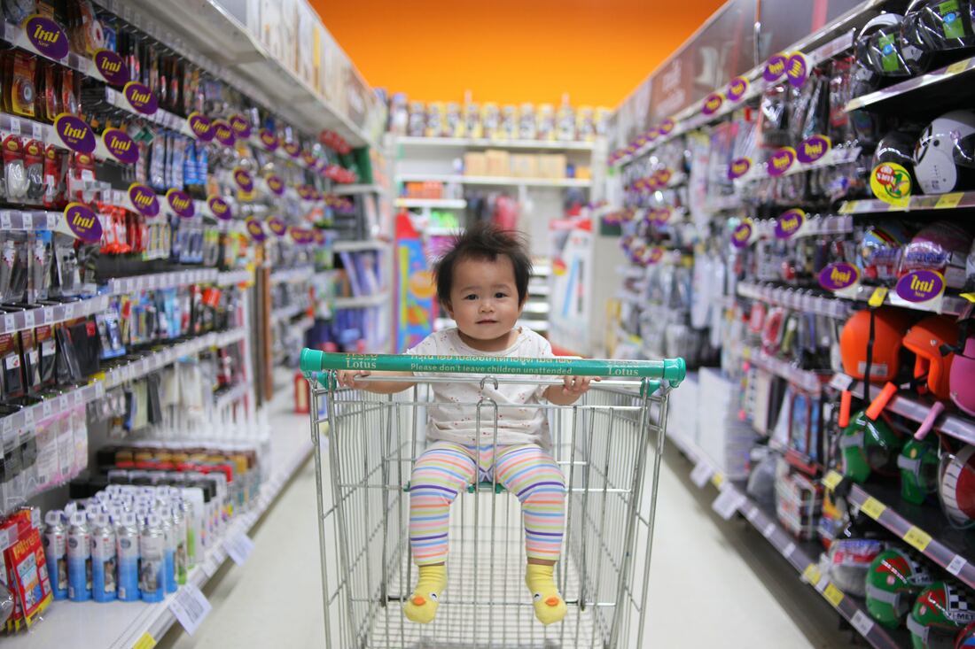 Cute asian baby in shopping cart - overwhelmed